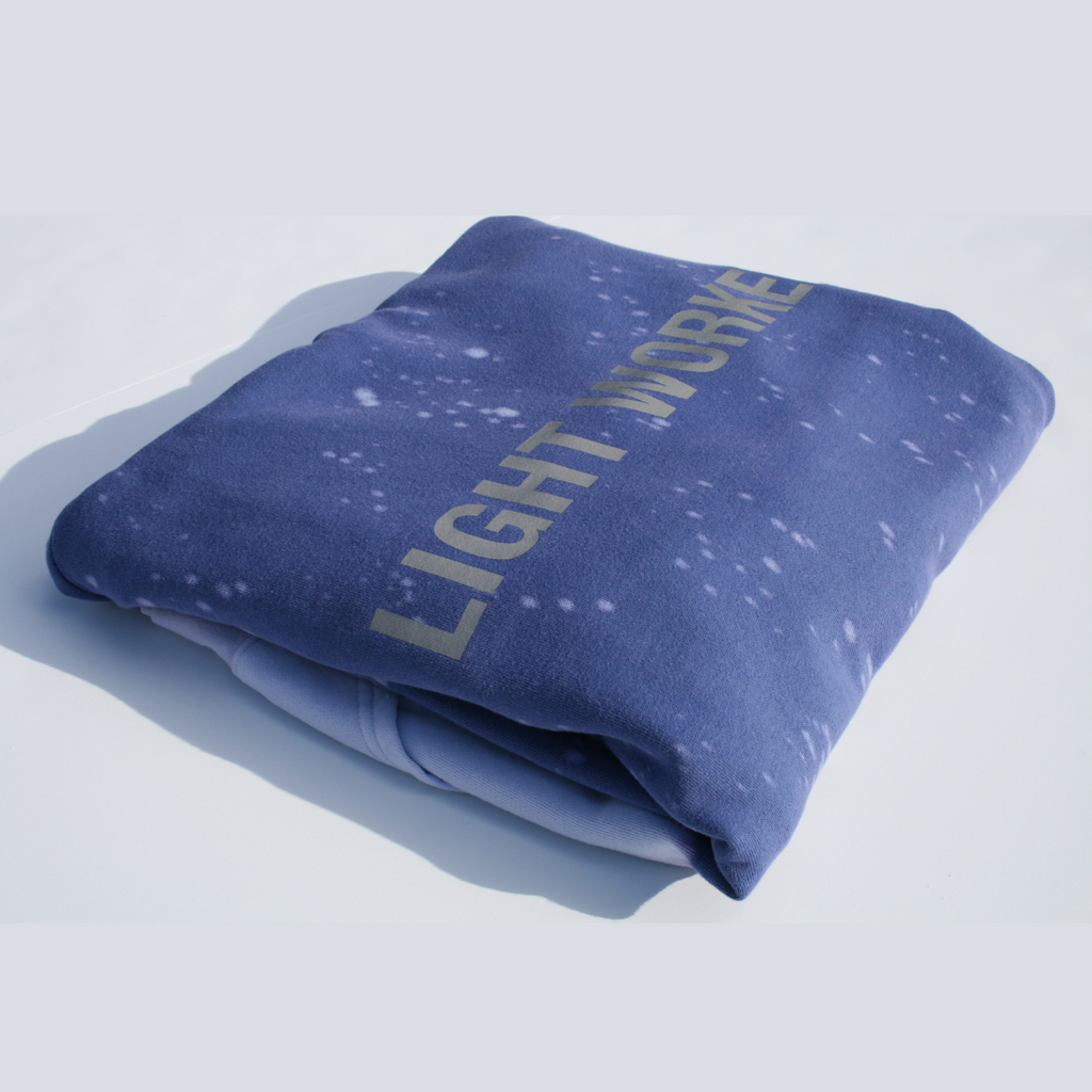 A folded, dark blue blanket with white specks and the words "LIGHT WORK" printed in large letters on it sits against a plain background, resembling the iconic vibes of a Limited Edition Light Worker Hoodie in Indigo Child by GFLApparel.