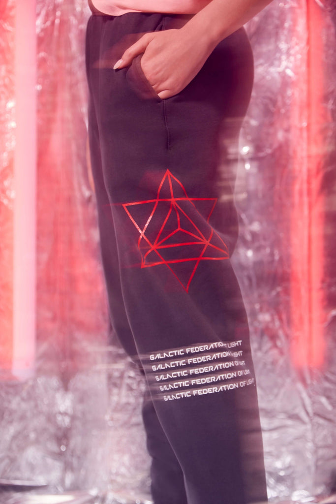 A woman wearing HYPERGALACTIC PANTS IN SPACE GLOW sweatshirt by GFLApparel with a red star on it.