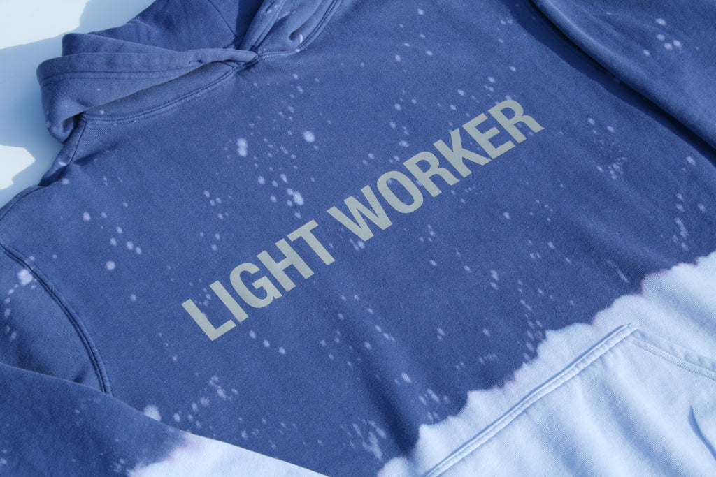 A blue and white tie-dye "Limited Edition Light Worker Hoodie in Indigo Child" with the words "LIGHT WORKER" printed in large, white letters across the chest. This limited edition hoodie by GFLApparel features a hood and long sleeves, perfect for any Indigo Child.