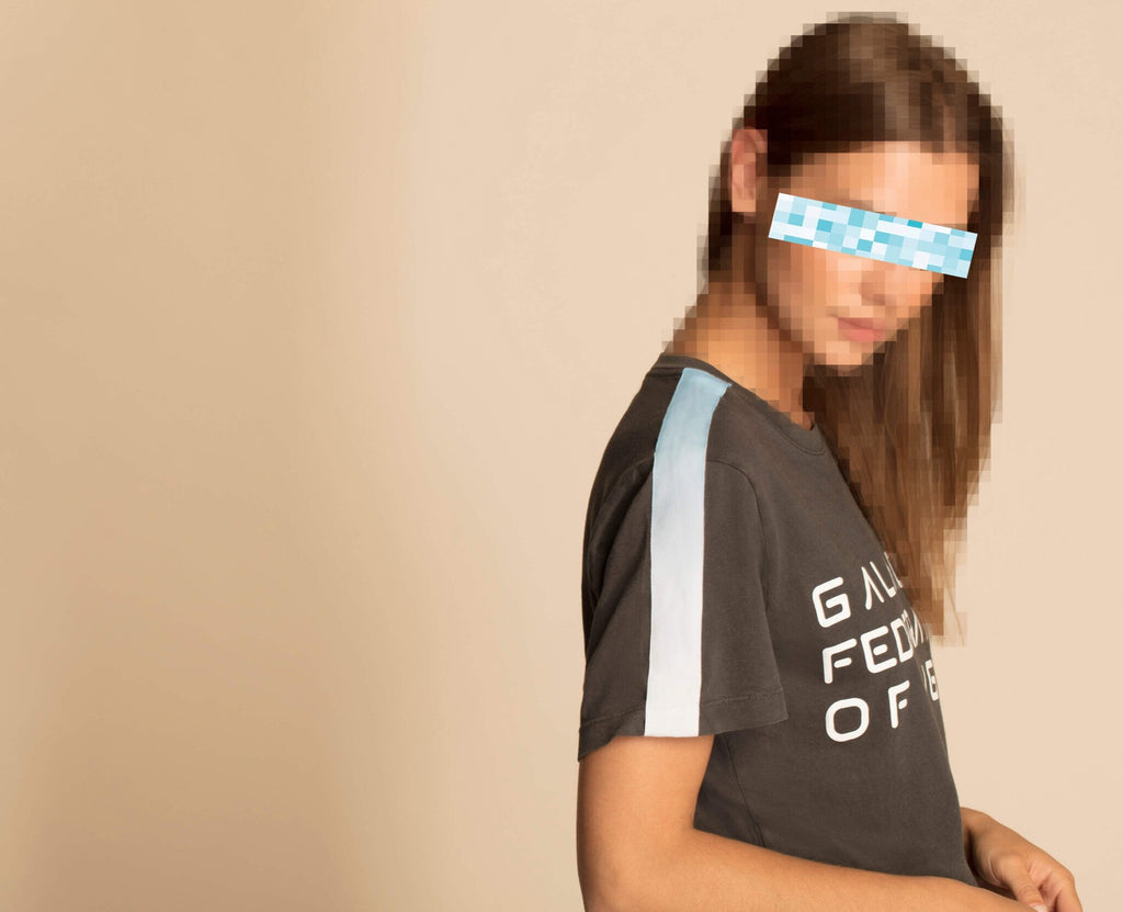A woman wearing a GFL STACK TEE IN SPACE GLOW t- shirt with a blue stripe.